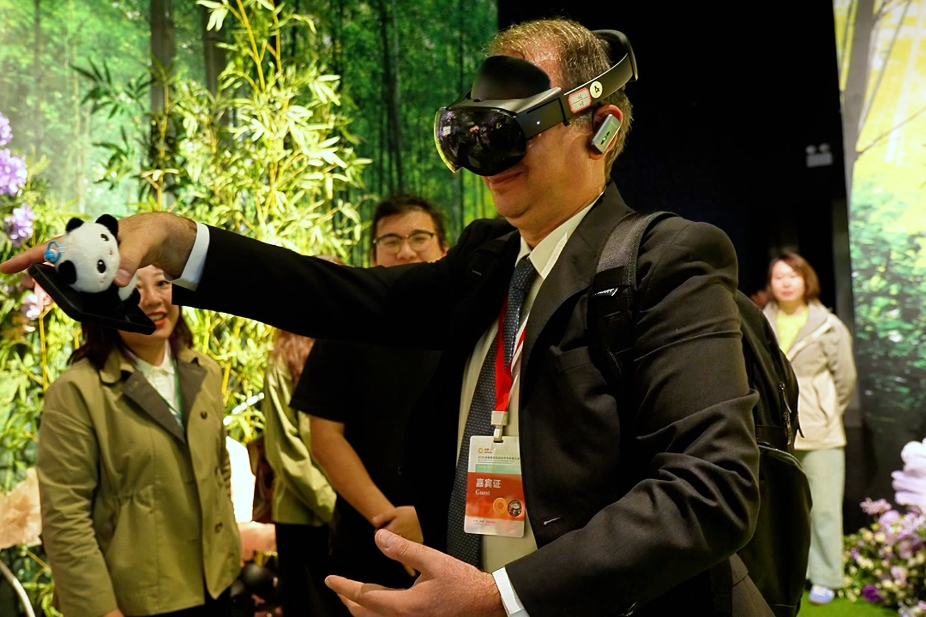 A delegate in a headset reaching out inside the physical bamboo set at the Chengdu Panda Base