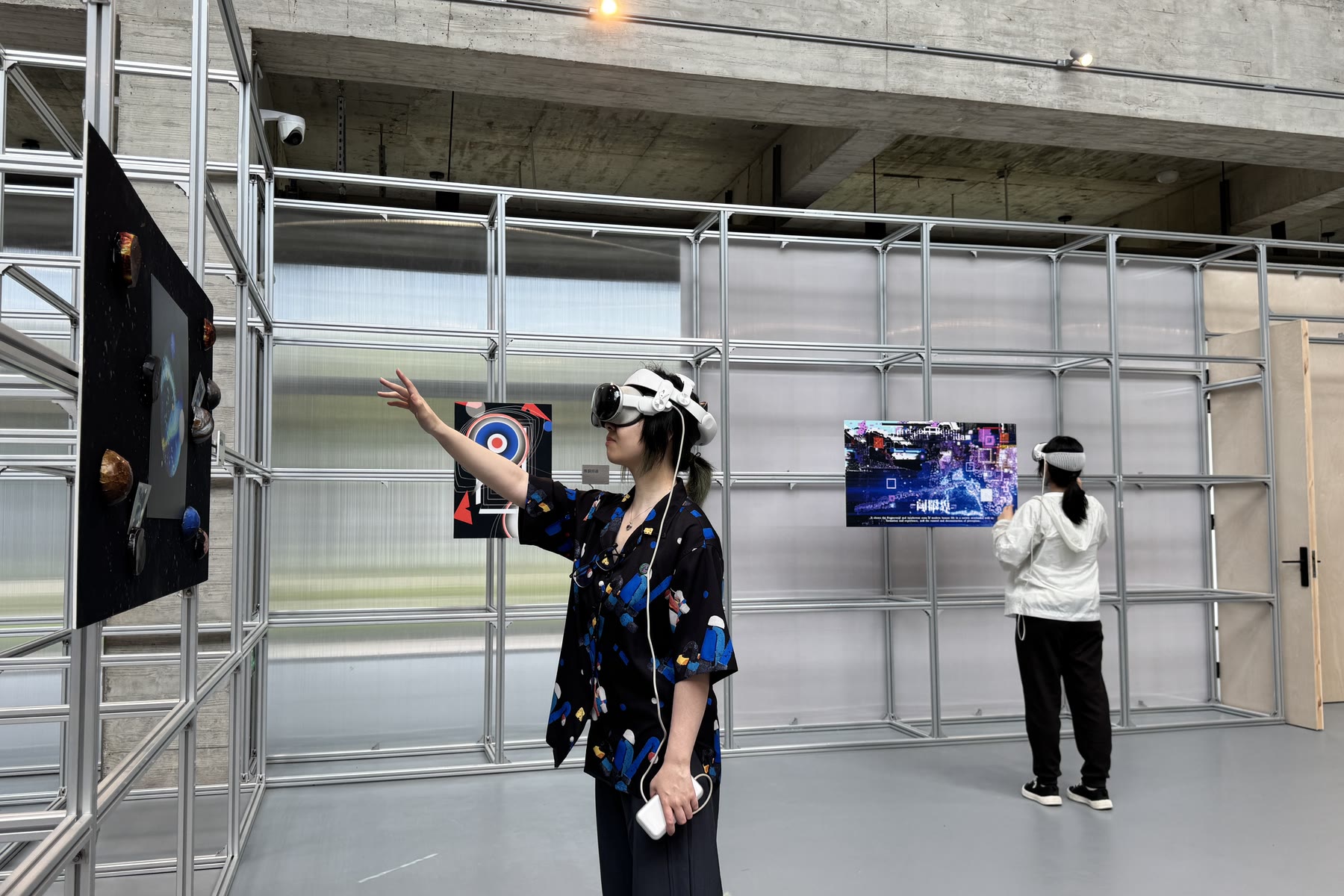 一位参观者戴着头显，伸手触碰锚定在展墙上的空间作品